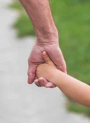 man and child walking near bushes during daytime