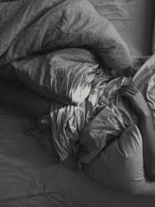 person lying on bed holding blanket